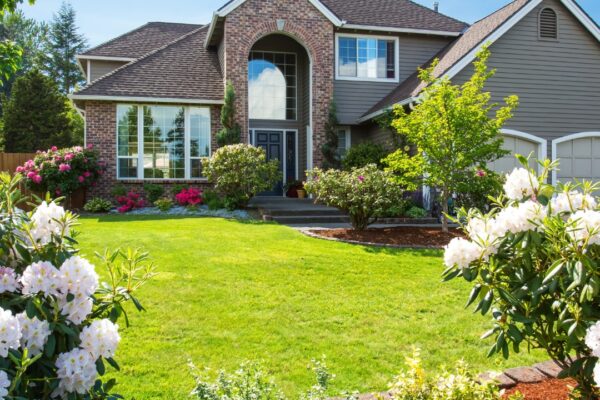 brick home with landscaping and lush green lawn